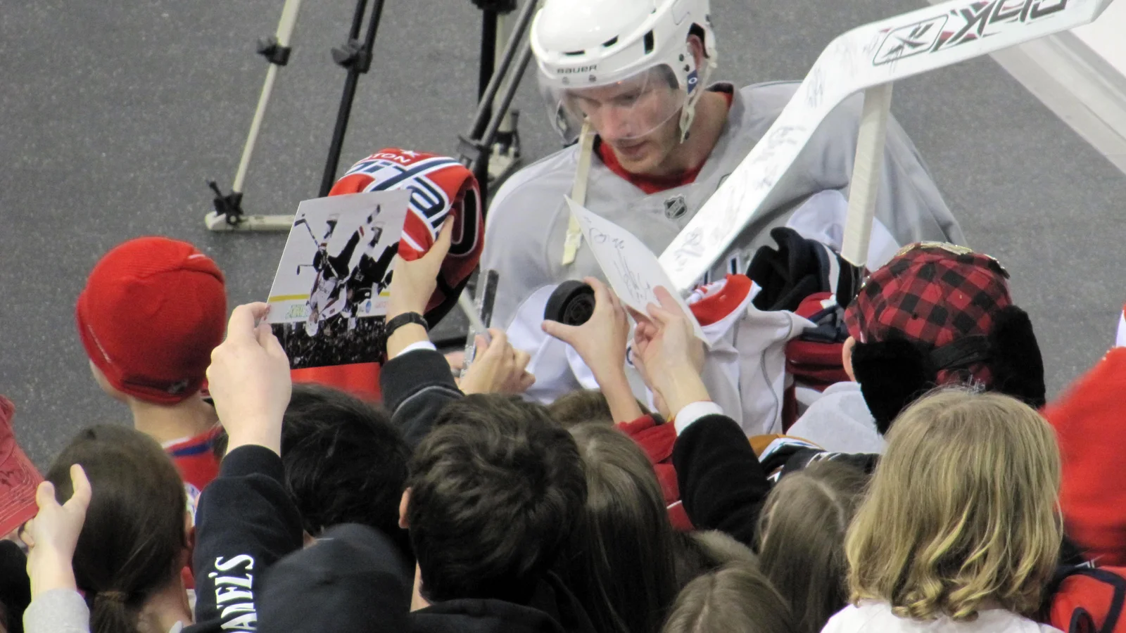 Washington Capitals player signing items for fans after a team practice