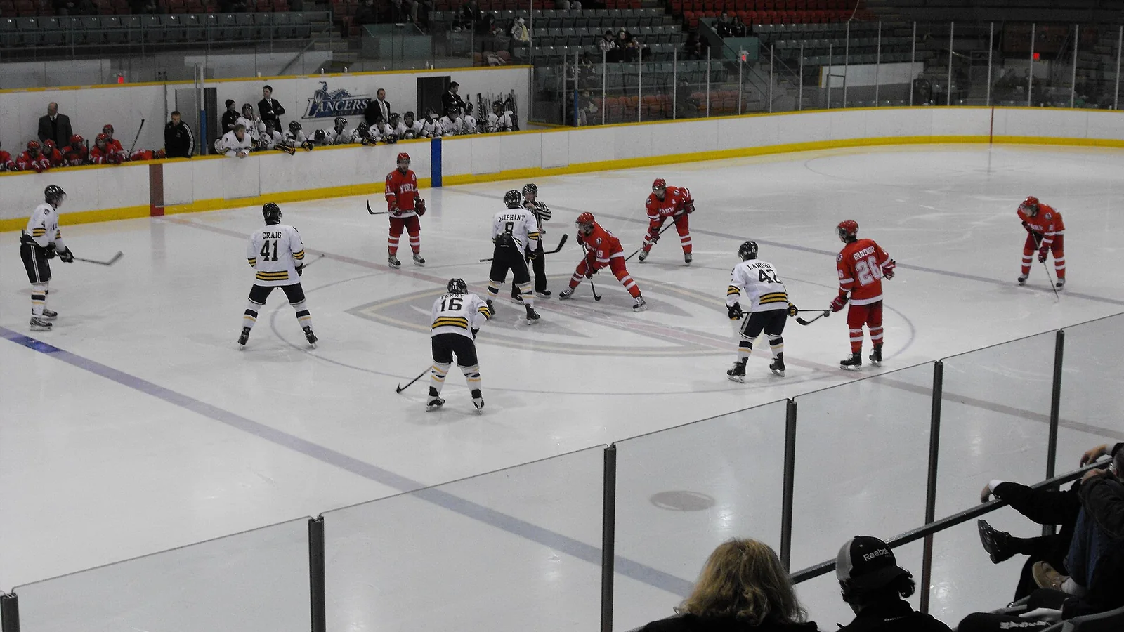 Two ice hockey teams line up for a faceoff during a game
